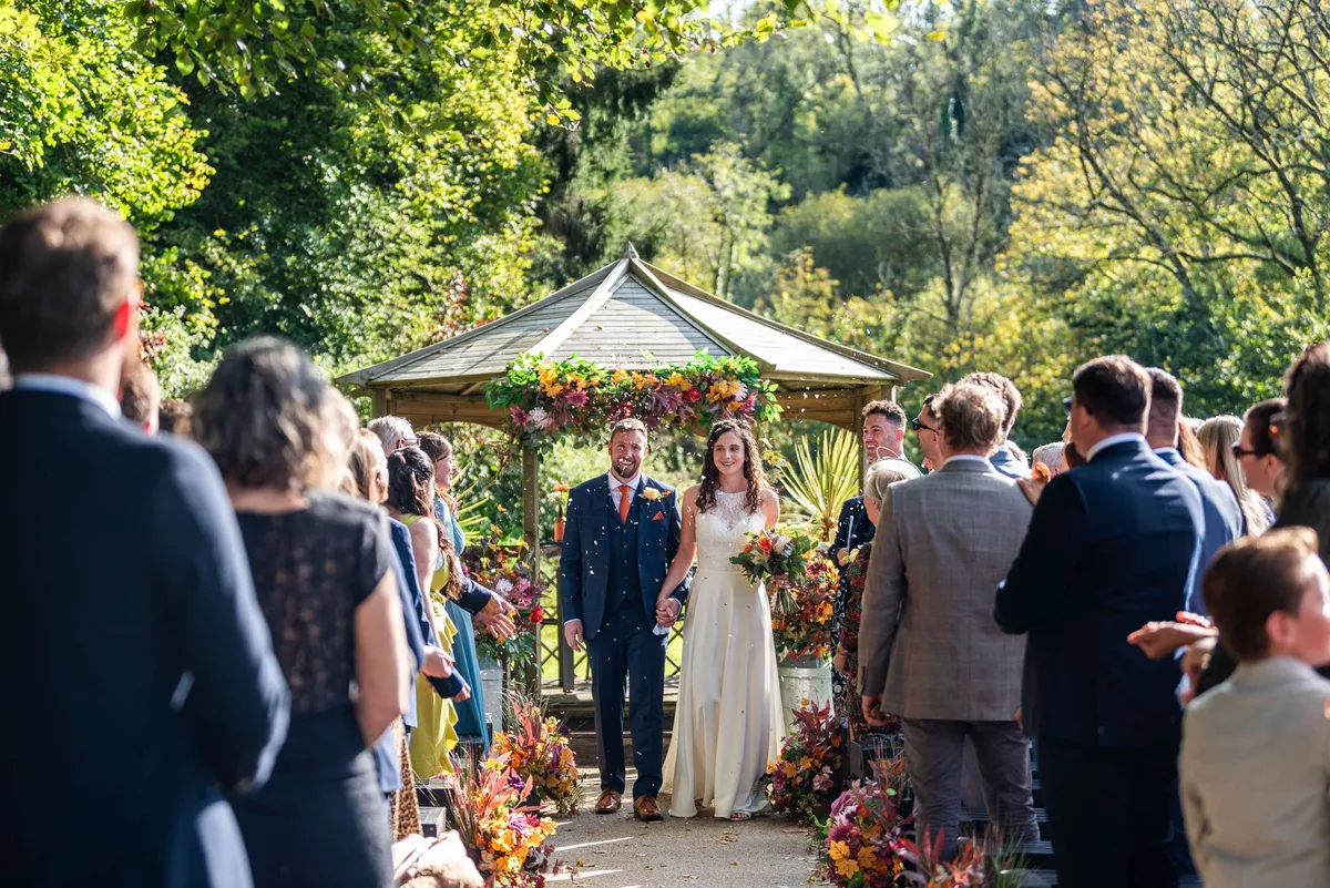 Outdoor ceremony with colourful meadow florals leading to a gazebo
