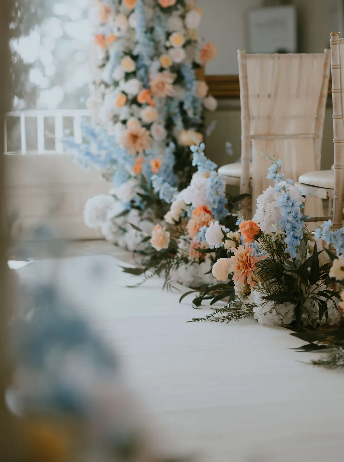 Close up of pale blue, peach and white meadow arrangements along an aisle at Kingston Maurward