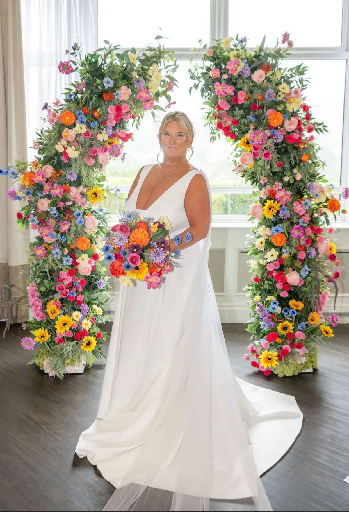 Bride with a bright meadow bouquet in front of colourful floral pillars