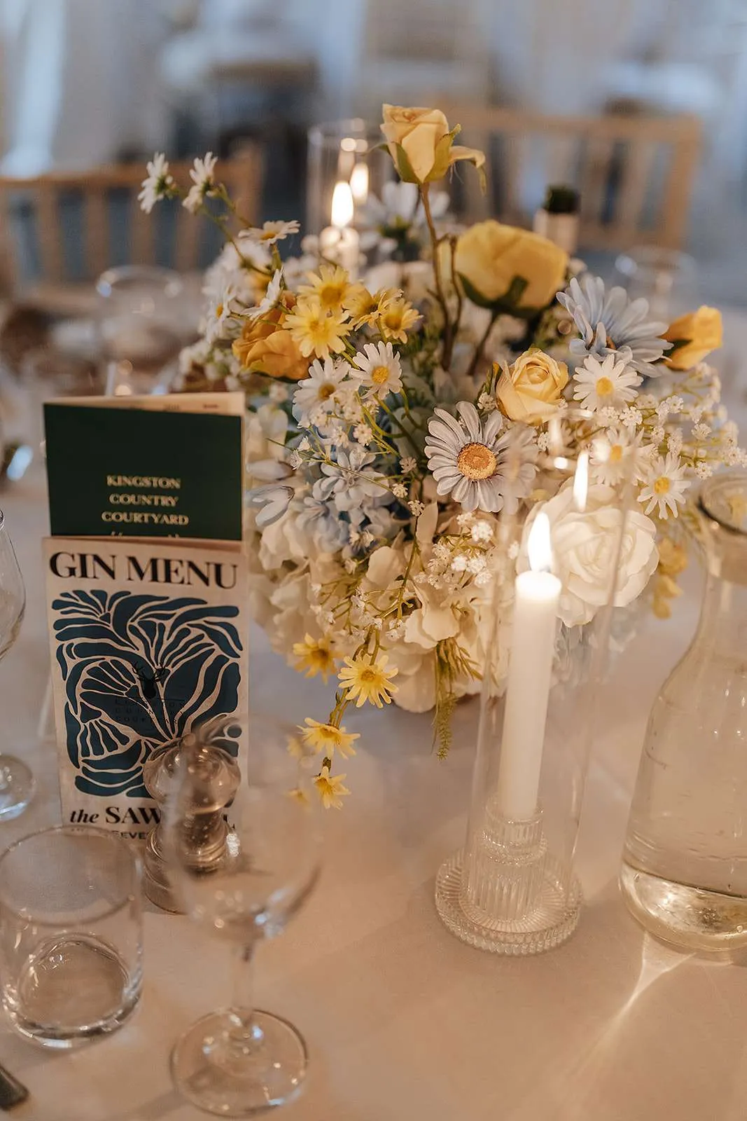 Yellow and white footed bowl arrangement with candles beside a table menu