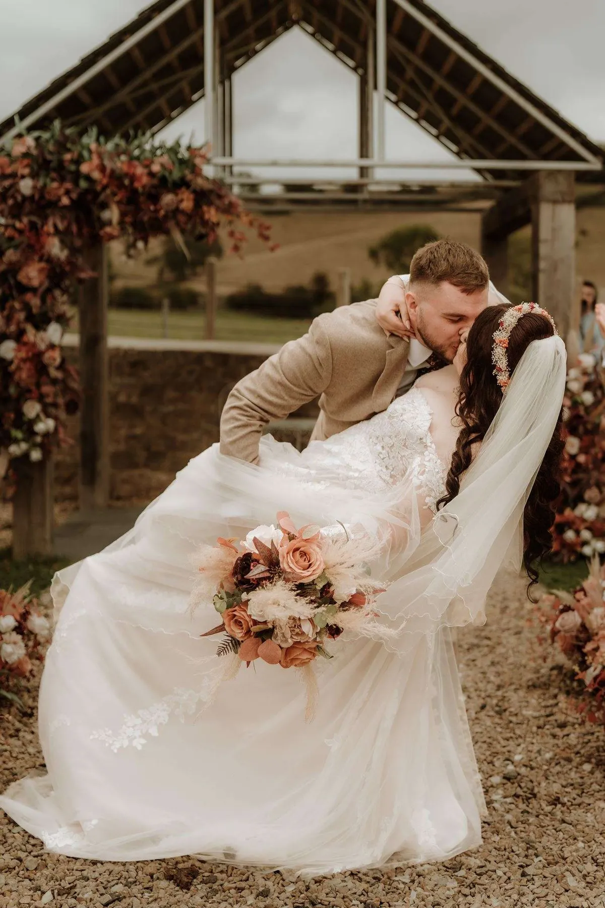 Couple kissing beneath an oak arbor dressed with autumnal florals