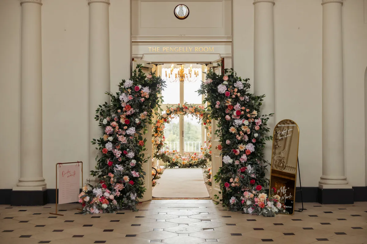 Pink, peach and white floral pillars framing a doorway in a grand hall