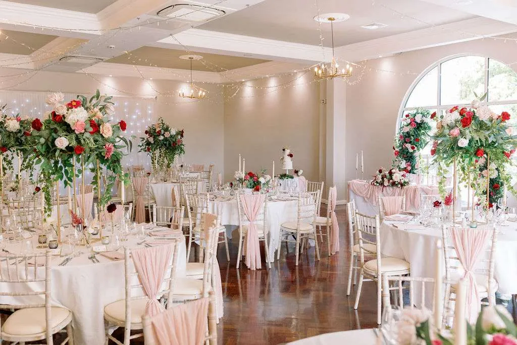 Reception room with tall red and white podium arrangements on every table
