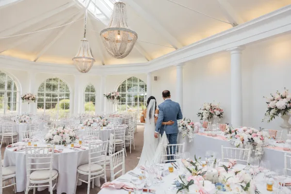 Reception room with blush and white table florals beneath chandeliers