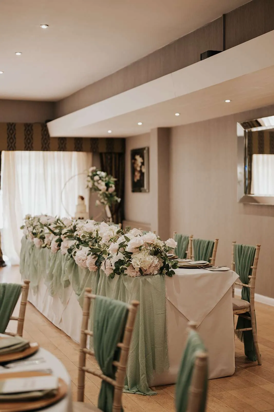 Long top table dressed with a full garland of white and green florals