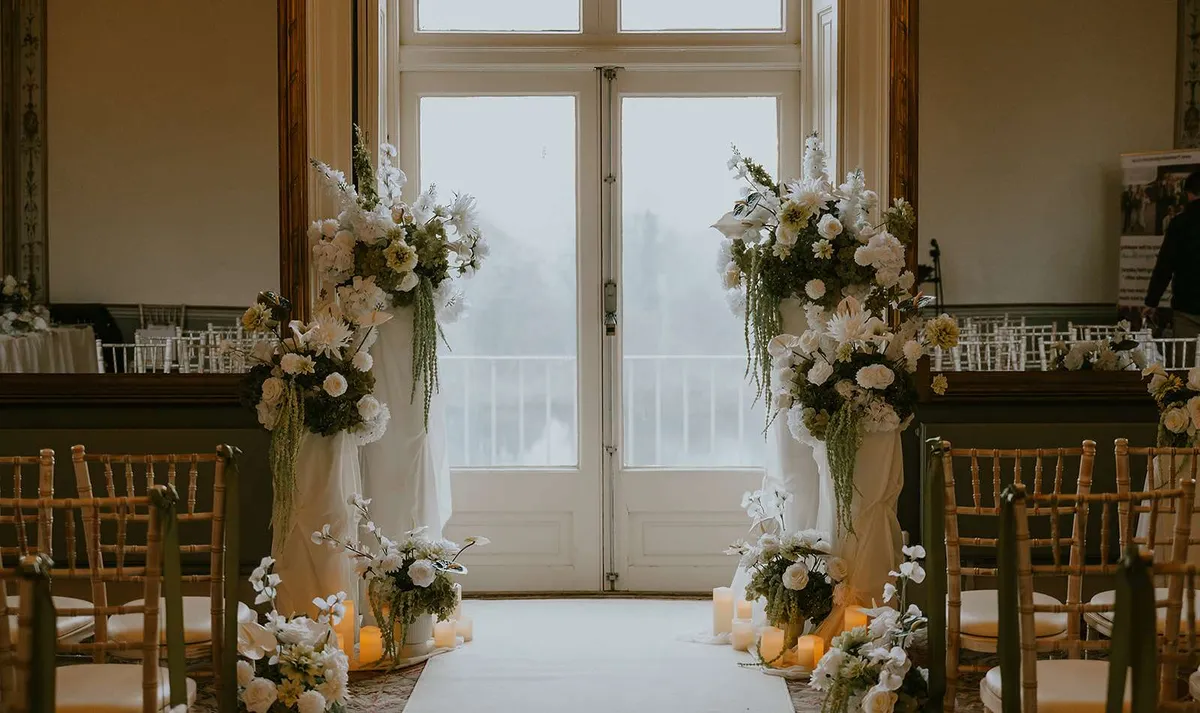 White floral urns on plinths framing tall glass doors